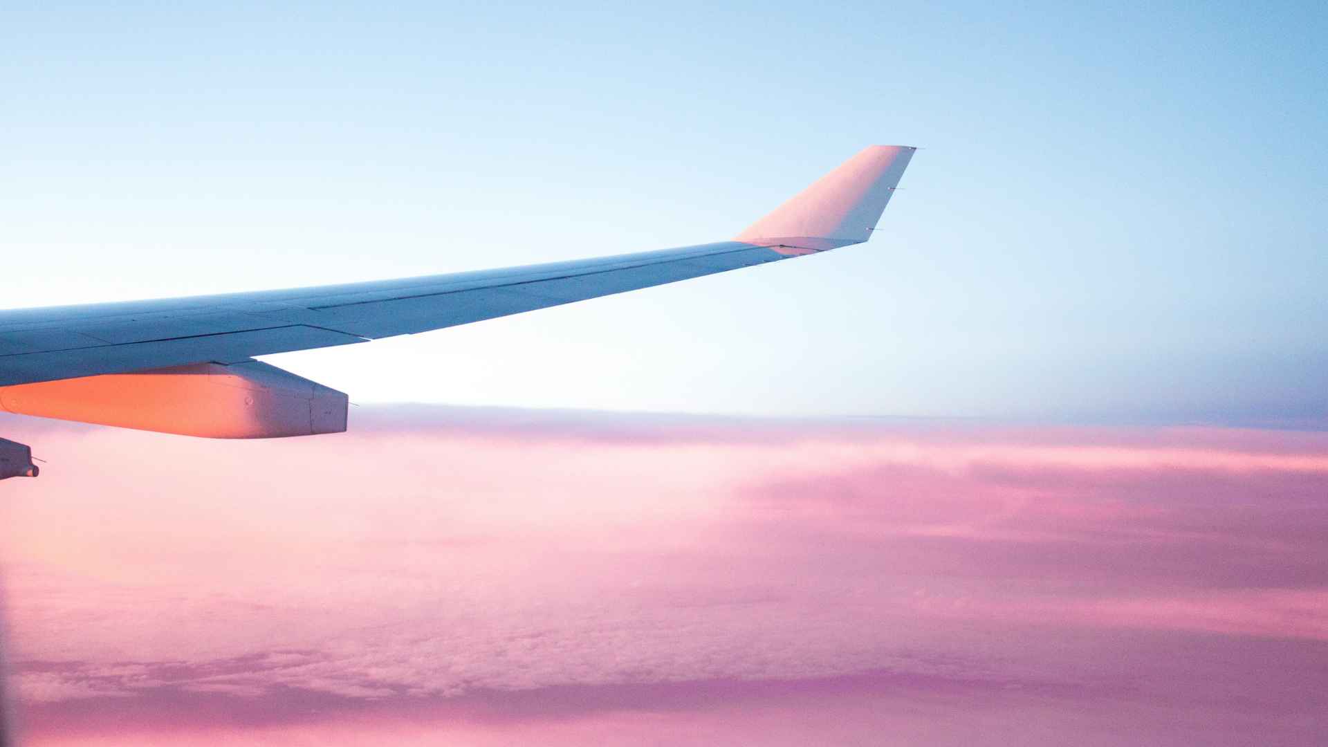 Ala di un aereo su nuvole rosa, metafora per risparmiare per realizzare i desideri